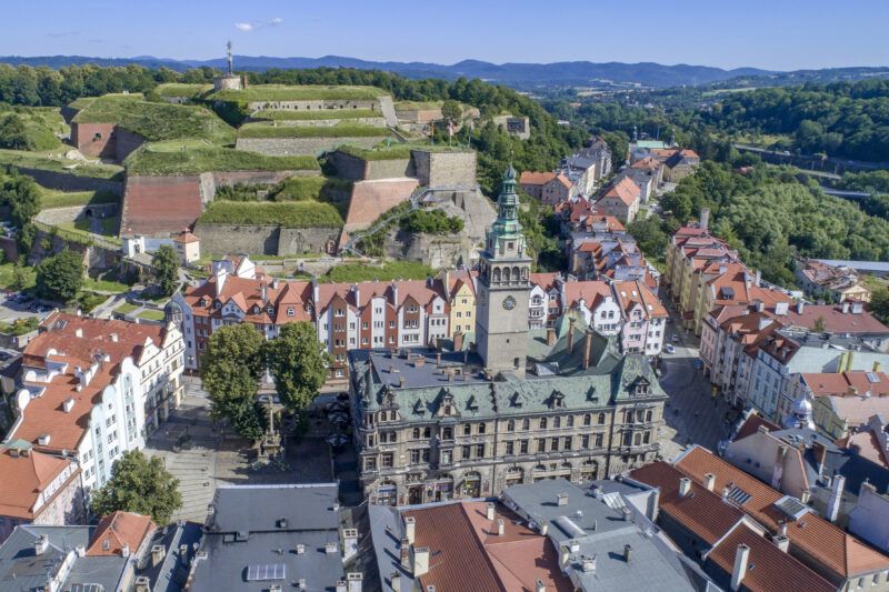 Zdjęcie z lotu ptaka na zabudowania średniej wielkości miasta z potężną twierdzą w tle