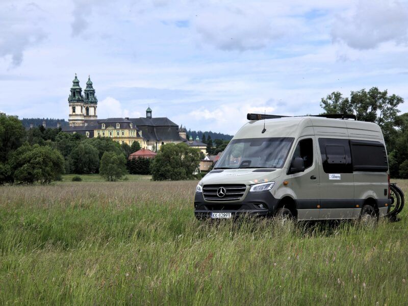 Panorama na opactwo w Krzeszowie z camperem zaparkowanym w trawie