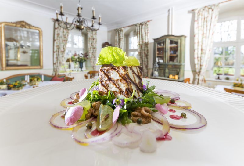 Zdjęcie przedstawia wykwintne darnie na talerzu w scenerii zabytkowego pałacu