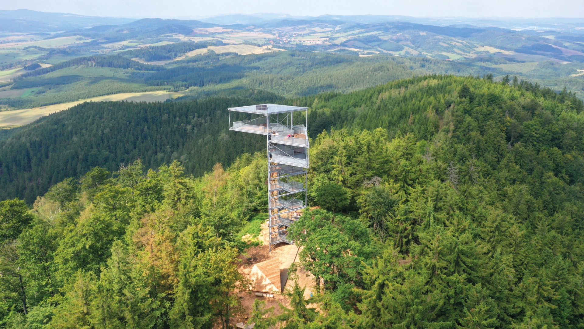 Widok z lotu ptaka na zalesiony szczyt z widoczną wieżą widokową