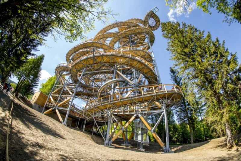 Zakręcony spiralnie wysoki taras widokowy usytułowany między drzewami.