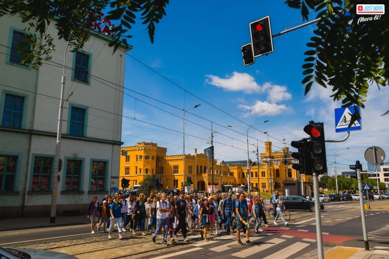 Grupa turystów - wycieczka przechodzi przez przejście dla pieszych we Wrocławiu na tle dworca wrocław główny