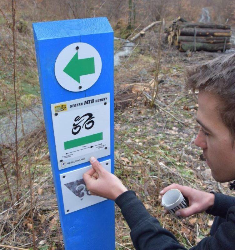 Mężczyzna ogląda tabliczkę Strefy MTB Sudety