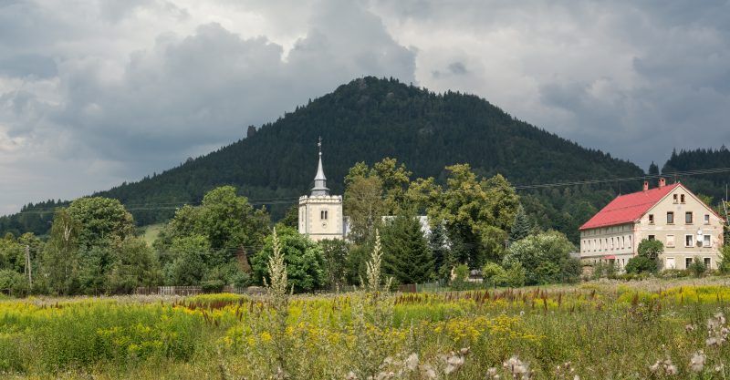 widok na górę w zachmurzony dzień, z przodu widać dwa budynki, kościół oraz biało-czerwony dom