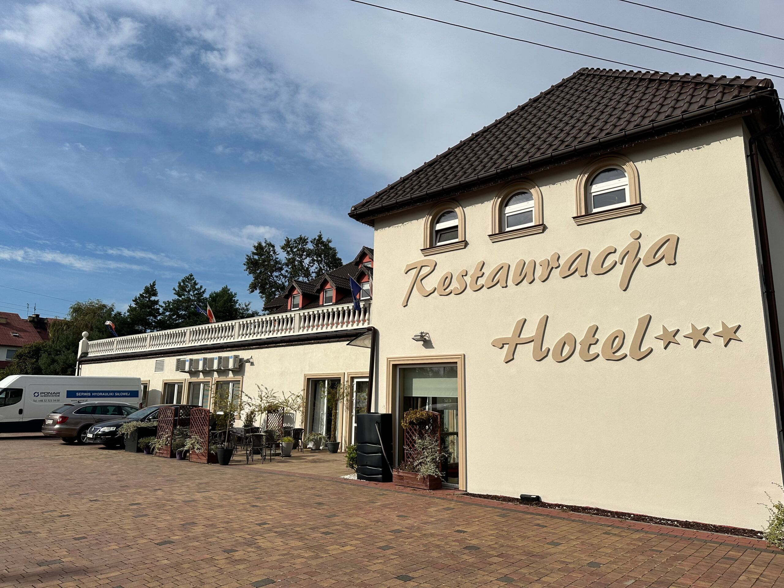Widok na elewację frontową budynku z wielkim napisem "restauracja, hotel***"