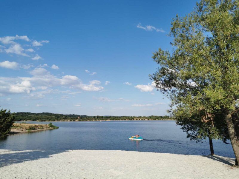 Zdjęcie przedstawiające piaszczystą plażę i turystów wypoczywających na wodzie