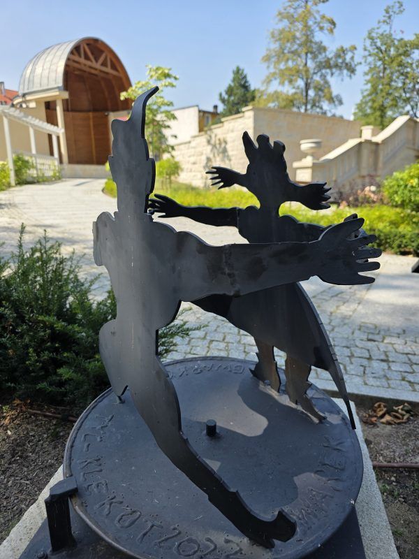 Metalowa rzeźba na tle amfiteatru w Złotym Stoku