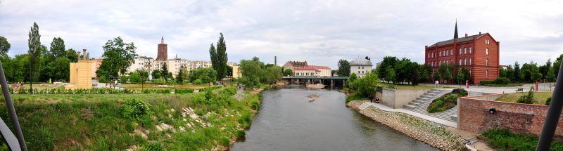 panorama rzeki, po bokach rzeki znajduję się zabudowanie, po lewej stronie budynki są żółte a po prawej czerwone