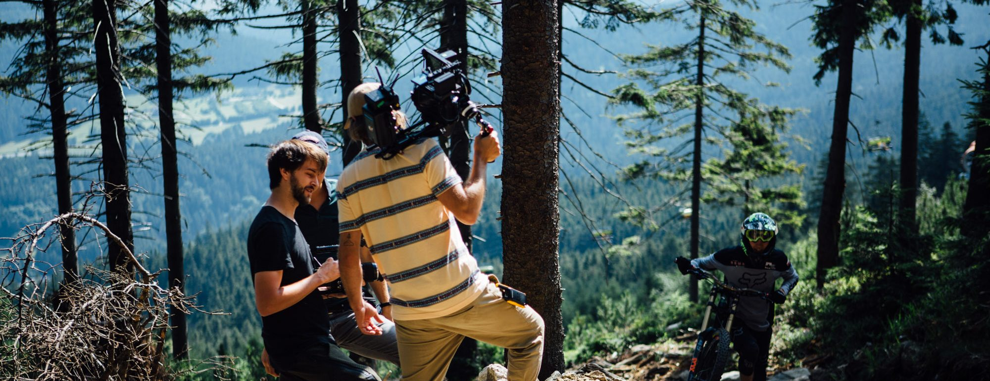 Filmowy stoją na zboczu góry z kamerą w otoczeniu lasu