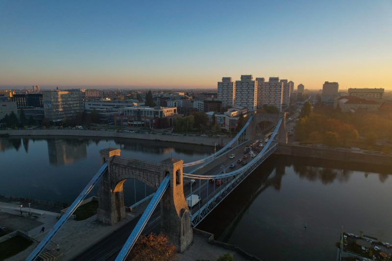 widok od boku na niebieski ogromny most nad szeroką rzeką, zdjęcie wykonane o wschodzie słońca