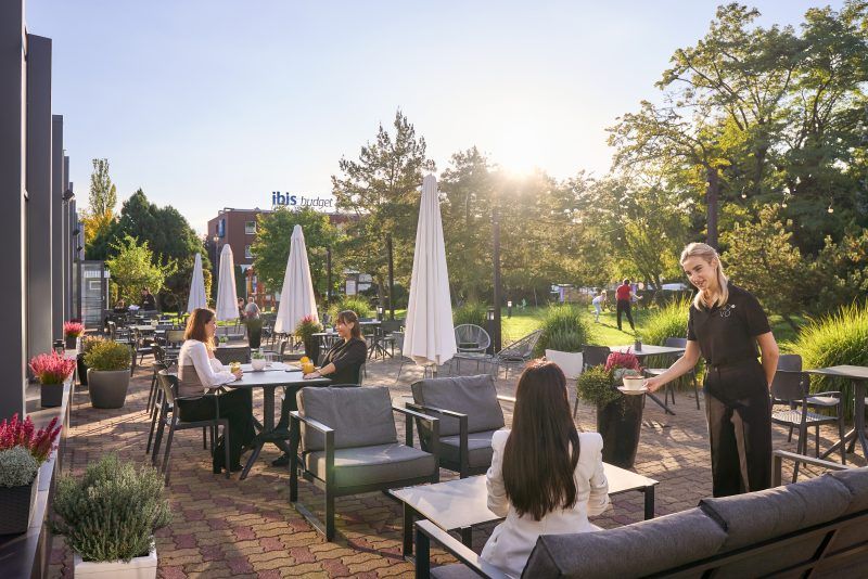 Zdjęcie tarasu ze stolikami i klientami restauracji siedzącymi przy stolikach