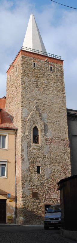 Zdjęcie starej kamiennej wieży w Bystrzycy Kłodzkiej. Zdjęcie wykonane z poziomu chodnika.