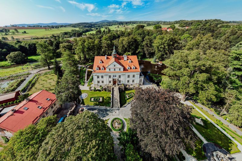 Zdjęcie przedstawia widok z lotu ptaka na Pałac Ciechanowice widoczny od frontu. W tle widoczna fantastyczna panorama Sudetów