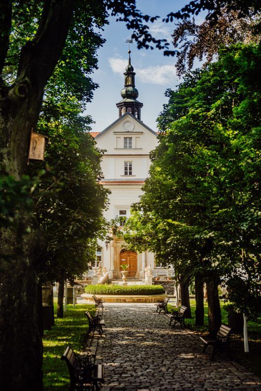 Widok na chodnik prowadzący do pałacu z wyraźnie widoczną wieżą.