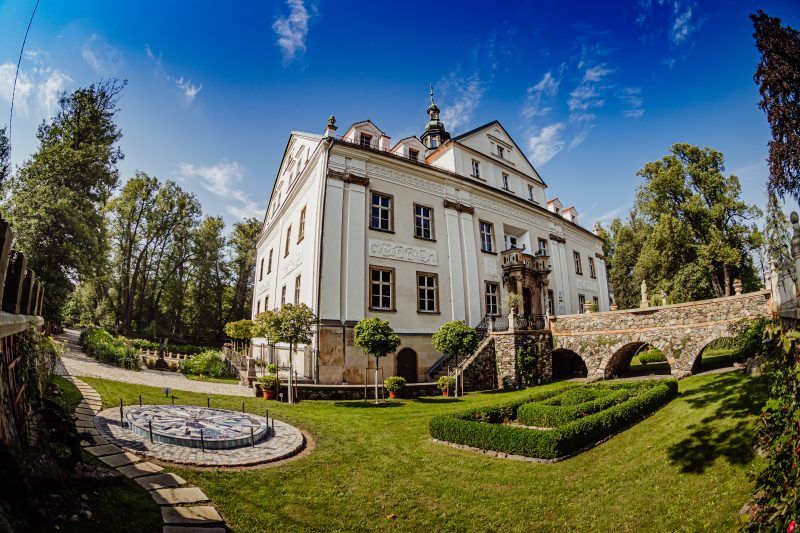 Zdjęcie przedstawia fasadę oraz mostek prowadzący do wejścia głównego do pałacu Ciechanowice