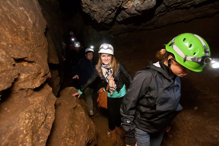 Grupa turystów z kobietą i dziećmi spoglądającymi w kadr na trasie turystycznej w Jaskini Radochowskiej