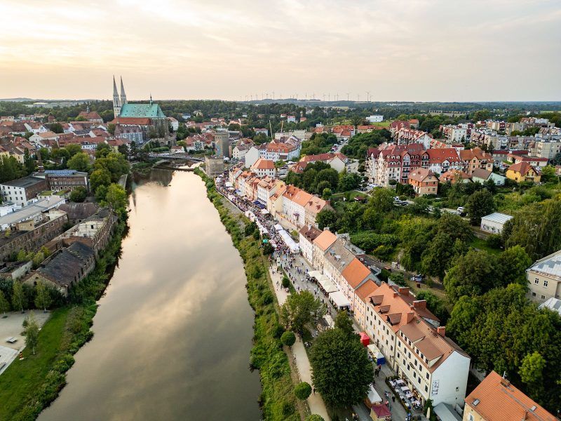 Widok z lotu ptaka na rzekę, przy której po prawej stronie znajduje się szereg budynków
