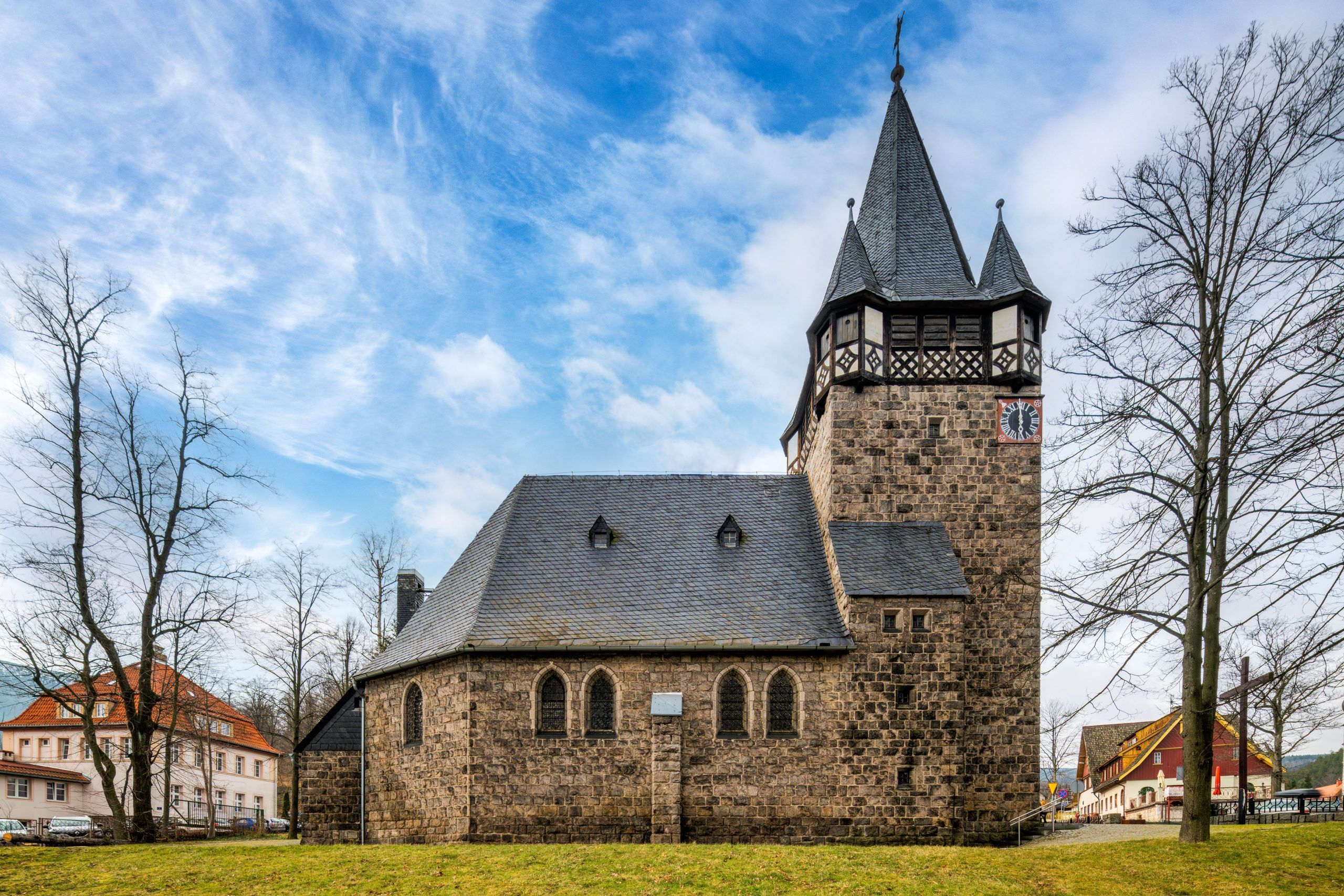 Neogotycka świątynia z ciemnego granitu, z wysoką wieżą i stromym dachem pokrytym łuskową blachą.