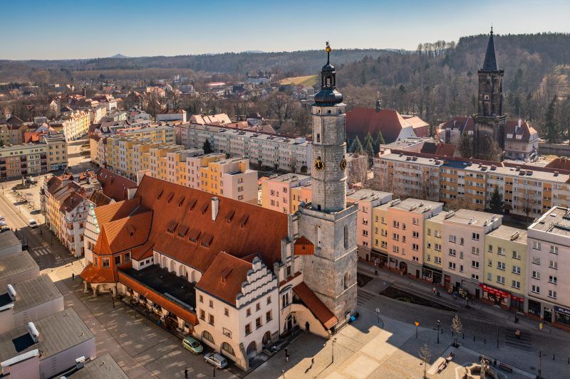 Imponujący budynek w stylu renesansowym z charakterystyczną wieżą zegarową, bogato zdobioną elewacją i strzelistymi dachami.