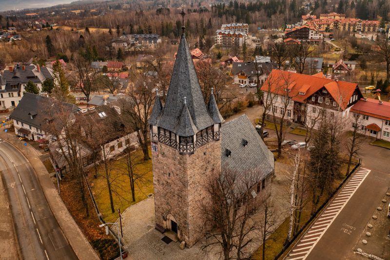 Neogotycka świątynia z ciemnego granitu, z wysoką wieżą i stromym dachem pokrytym łuskową blachą.
