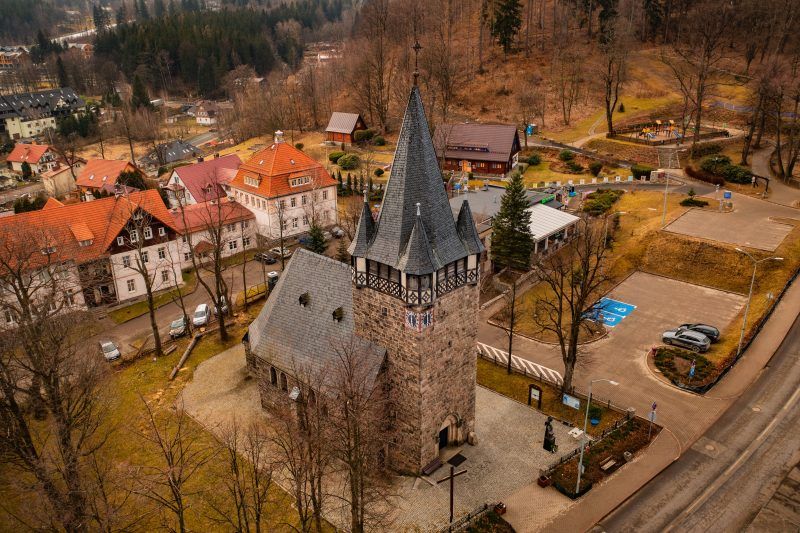 Neogotycka świątynia z ciemnego granitu, z wysoką wieżą i stromym dachem pokrytym łuskową blachą.