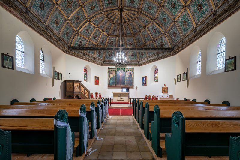 Wnętrze utrzymane w ciepłej, drewnianej stylistyce, z prostym układem i skromną dekoracją sakralną.