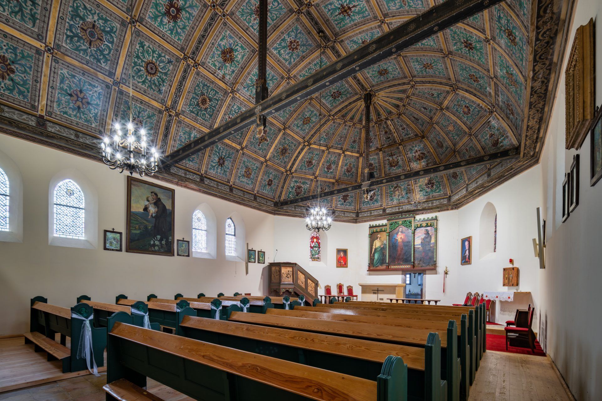 Wnętrze utrzymane w ciepłej, drewnianej stylistyce, z prostym układem i skromną dekoracją sakralną.