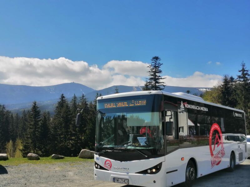 Biały autobus firmy Vip Travel na tle Karkonoszy