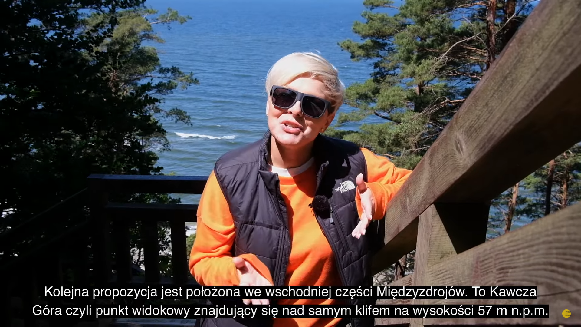 Kobieta w stroju sportowym spogląda w obiektyw kamery na tle morza bałtyckiego