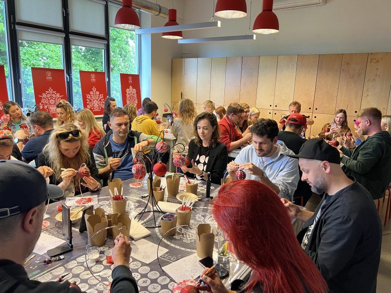 Grupa ludzi podczas warsztatów artystycznych. Grafika promocyjna Dni Karpia w Dolinie Baryczy w 2025 roku