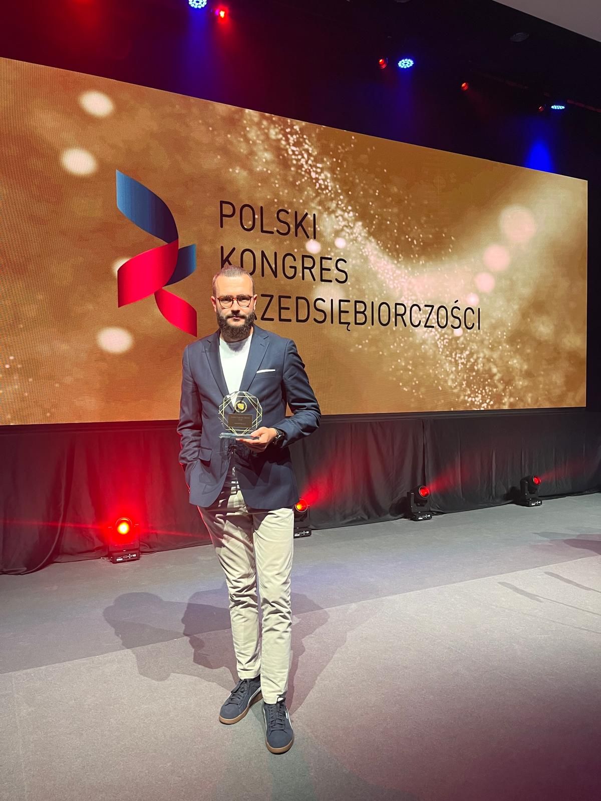 Mężczyzna w garniturze stoi na scenie podczas polskiego kongresu przedsiębiorczości