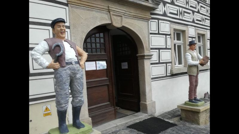 wejście do muzeum, po bokach drzwi stoją dwie wysokie figurki przedstawiające mężczyzn