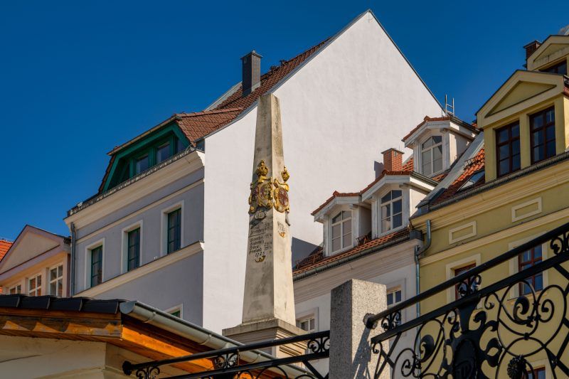 Kamienny, barokowy słup z herbami i inskrypcjami wskazującymi odległości do miast.
