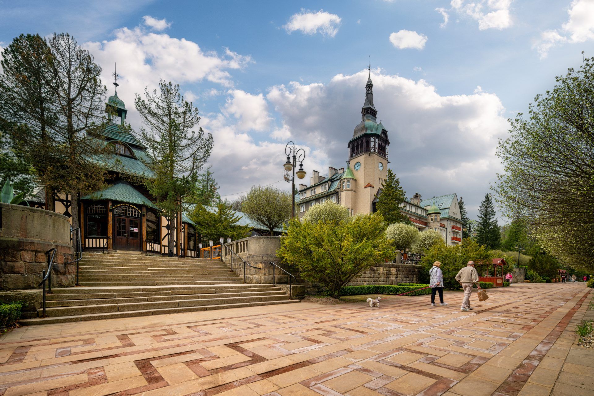 Na zdjęciu widać okazałą Halę Spacerową w Świeradowie-Zdroju – długą konstrukcję z drewnianymi zdobieniami, otoczoną zielenią i tętniącą uzdrowiskowym życiem.