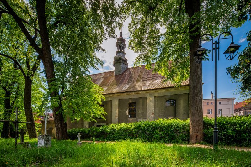 Na zdjęciu widać potężny, ceglany kościół św. Mikołaja z wysoką wieżą i ostrołukowymi oknami, stojący przy ząbkowickim rynku.