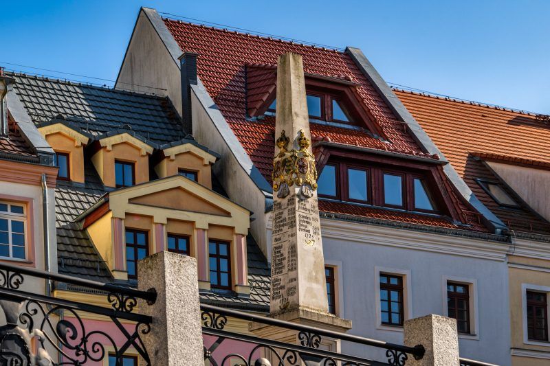 Kamienny, barokowy słup z herbami i inskrypcjami wskazującymi odległości do miast.