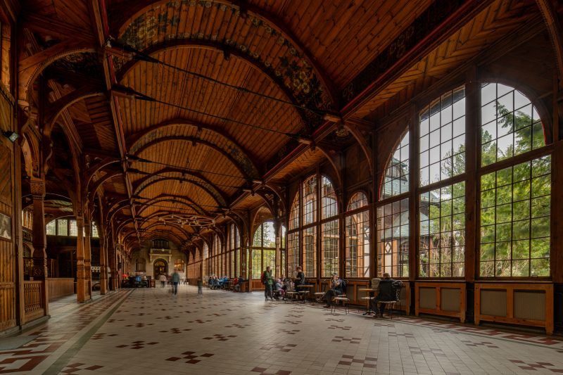 Na zdjęciu wnętrze Hali Spacerowej w Świeradowie-Zdroju – przestronna, pełna światła sala z drewnianymi kolumnami.