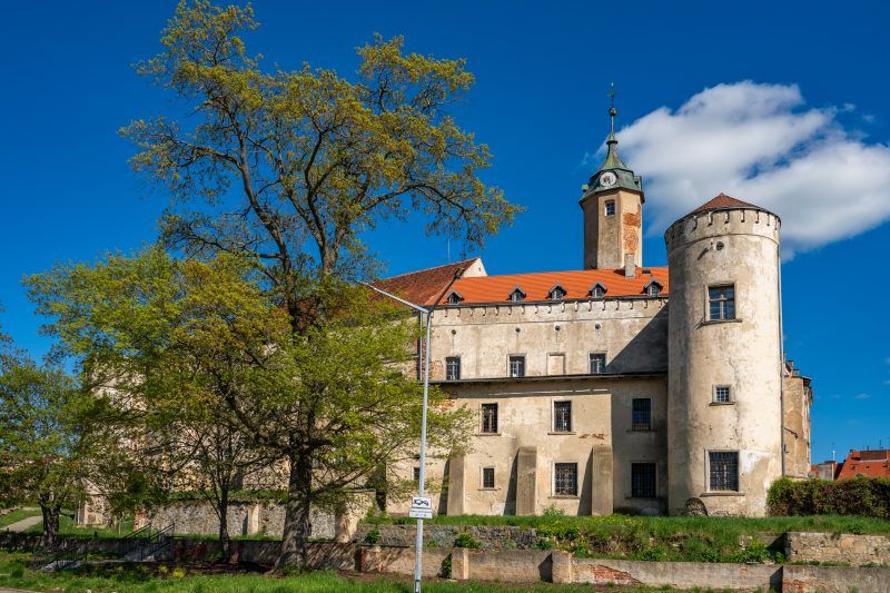 Na zdjęciu Zamek Piastowski w Jaworze wygląda jak solidna, jasnokamienna twierdza z wysoką, prostokątną wieżą i równymi murami dominującymi nad otoczeniem.