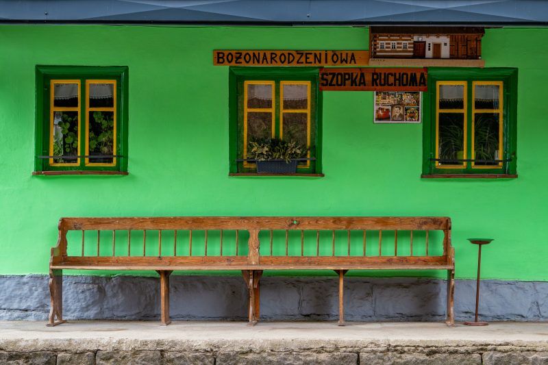 Na zdjęciu widać mały, zielony domek z żółtymi oknami.