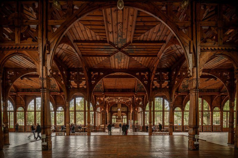 Na zdjęciu wnętrze Hali Spacerowej w Świeradowie-Zdroju – przestronna, pełna światła sala z drewnianymi kolumnami.