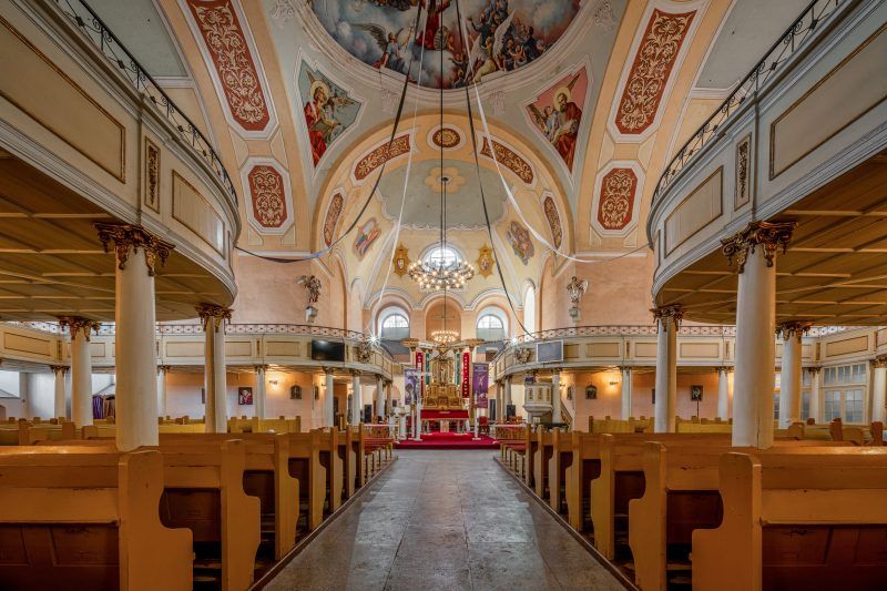 Na zdjęciu wnętrze Kościoła Łaski w Kamiennej Górze – przestronne, jasne wnętrze z bogato zdobionym ołtarzem, rzeźbionymi emporami i misternymi detalami barokowej architektury.
