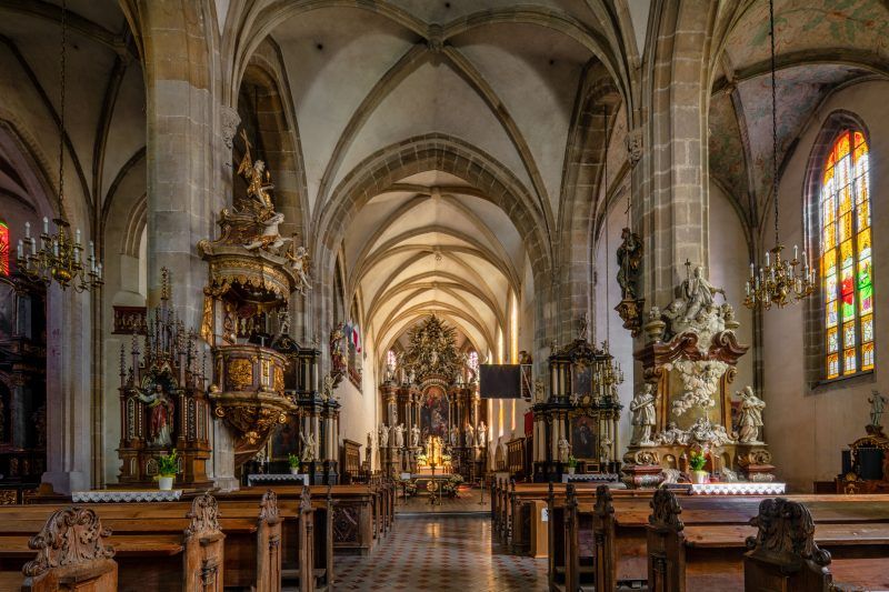 Wnętrze kościoła zachwyca wysoką, gotycką nawą, smukłymi filarami i bogato zdobionym ołtarzem, tworząc wrażenie przestrzeni i skupionej świętości.