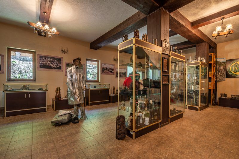Wnętrze muzeum z eksponatami dotyczącymi historii górnictwa na ścianach i w gablotach.
