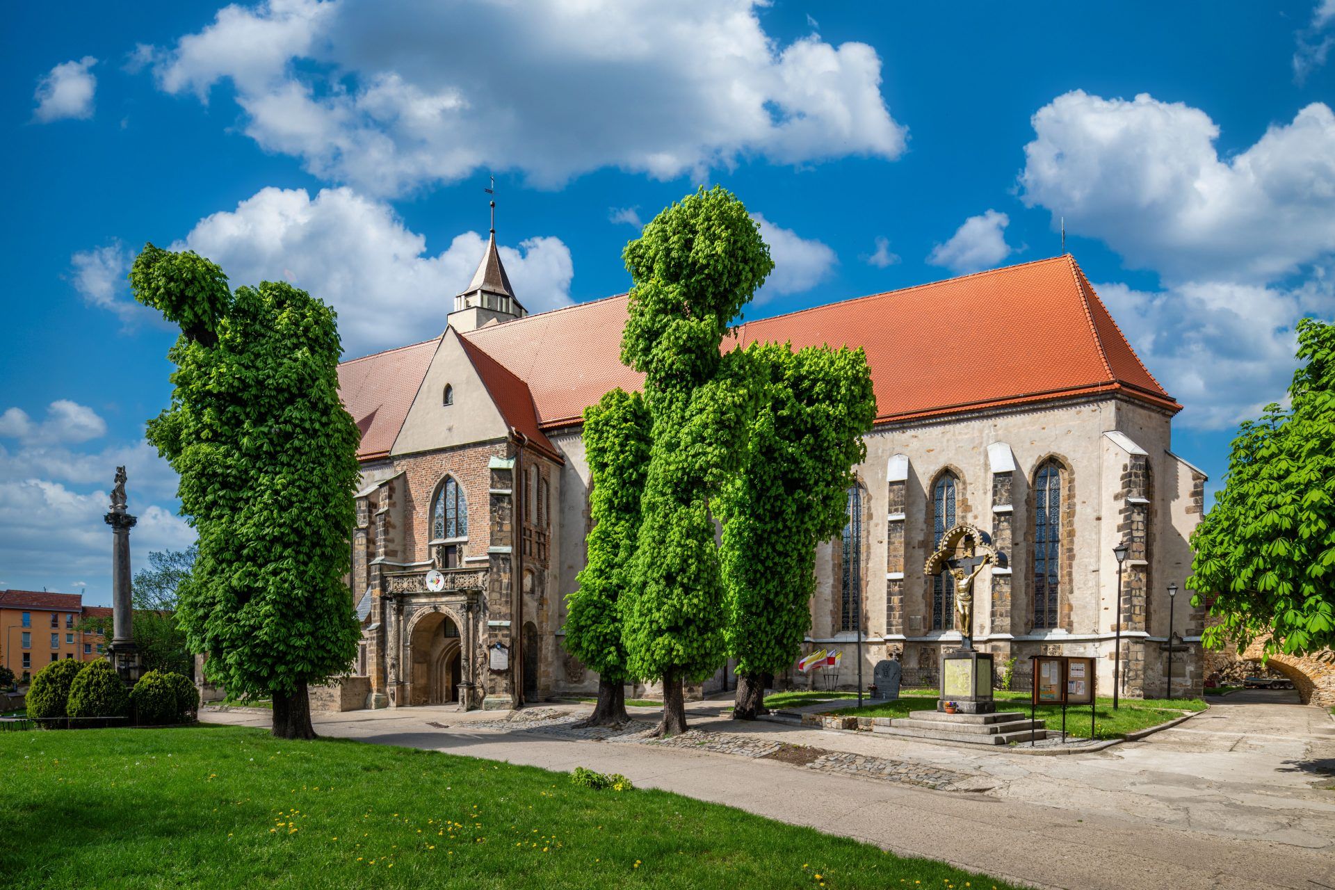 Monumentalna gotycka świątynia z wysoką wieżą i masywnymi, ceglastymi murami dominuje nad okoliczną zabudową.