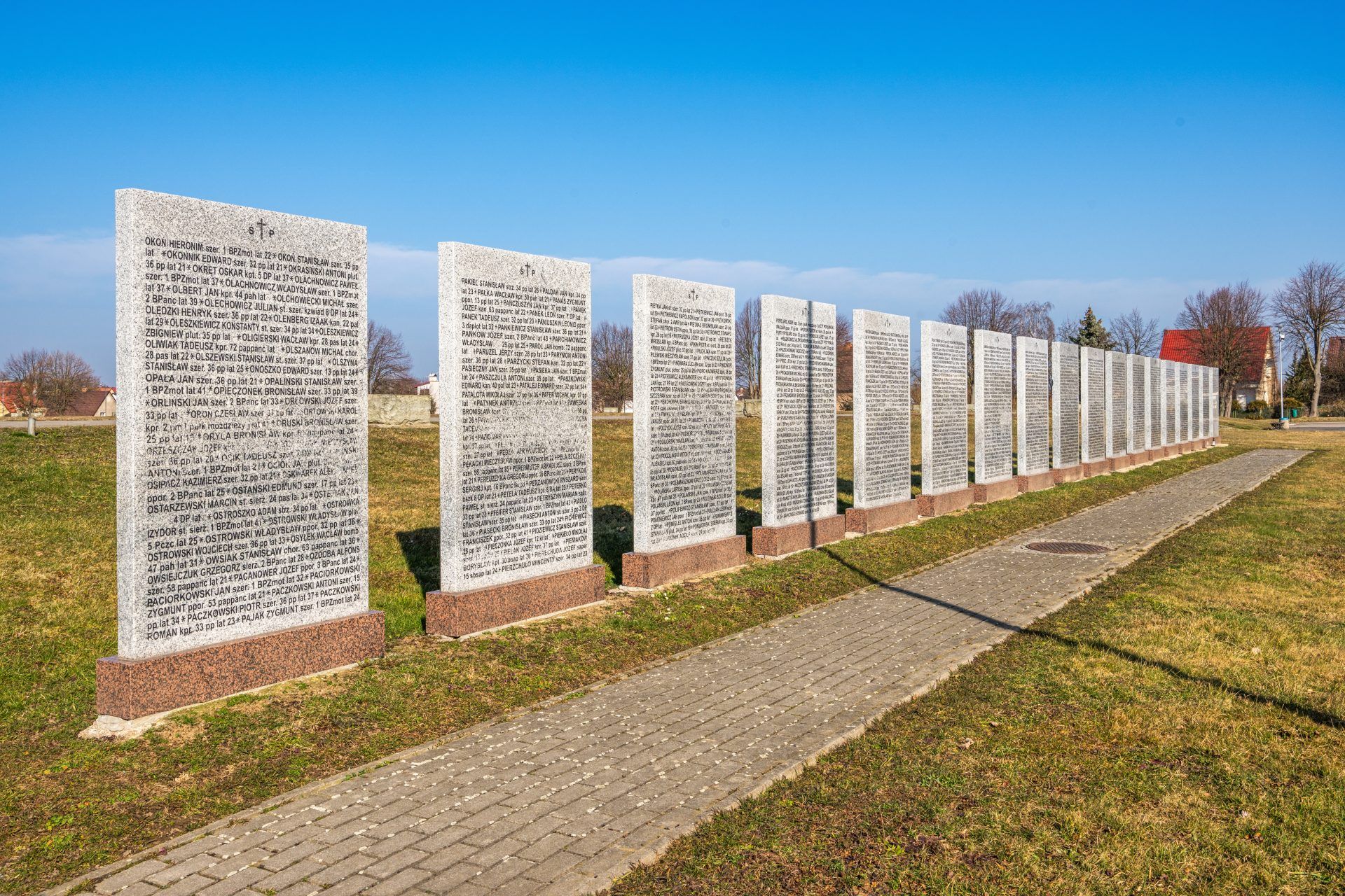 Na zdjęciu widać uporządkowany cmentarz z kamiennymi nagrobkami, otoczony zielenią, z zadbaną przestrzenią upamiętniającą żołnierzy II Armii Wojska Polskiego.