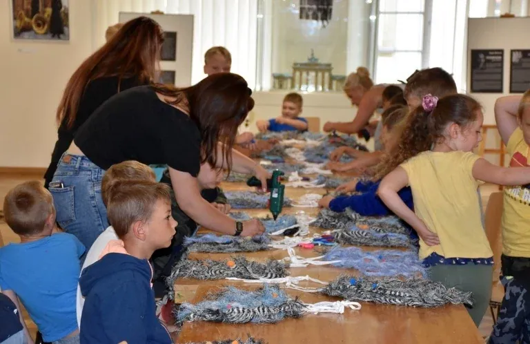 Grupa młodych turystów podczas warsztatów w muzeum tkactwa