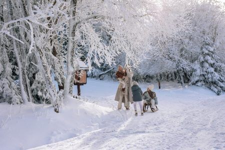 Cała rodzina turystów wraz dziećmi bawią się na sankach na śniegu w Karkonoszach