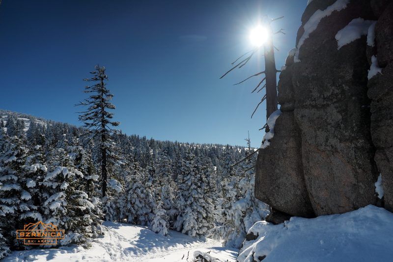 Przyroda wokół ośrodka narciarskiego z błękitnym niebem oraz słońcem wysoko nad horyzontem