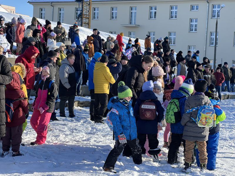 Zdjęcie przedstawia grupę dzieci i młodzieży podczas zabaw na śniegu