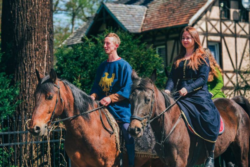 Mężczyzna i kobieta siedzą na koniu podczas jazdy i majówki historycznej w Zamku Kliczków